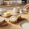 Hand holding USB rechargeable heated butter knife spreading softened butter onto artisan bread slice on kitchen counter; lifestyle morning use