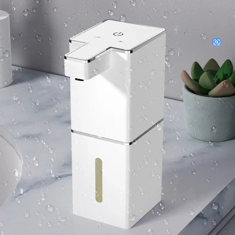 USB rechargeable automatic foam soap dispenser in white on wet marble bathroom countertop next to succulent plant
