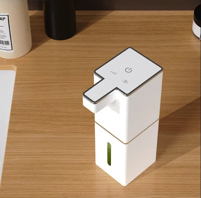 USB rechargeable automatic foam soap dispenser in white with green soap level indicator on wooden desk