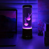 Color changing LED jellyfish night light glowing purple on desk next to monitor in dark room