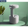 Gray anti-gravity humidifier with USB charging cable on green table next to plant
