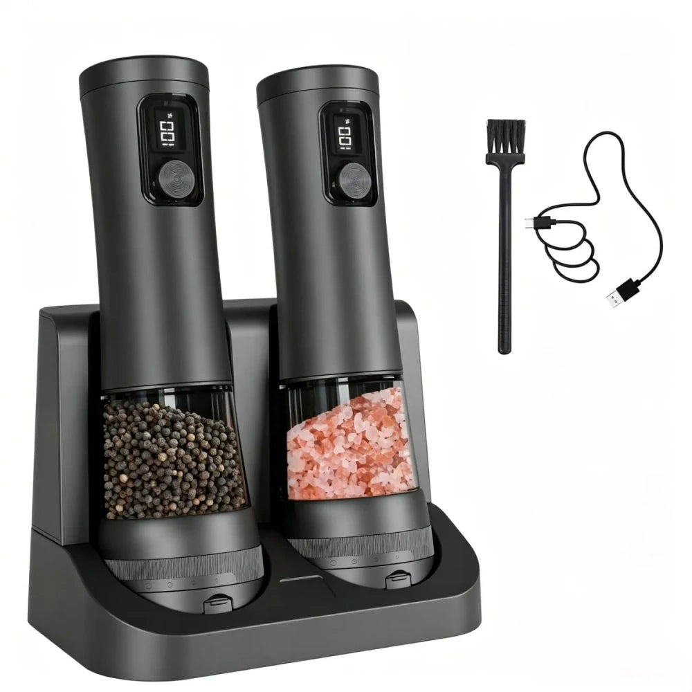 Dark grey electric salt and pepper grinder set on dual charging base with black cleaning brush and USB charging cable; peppercorns and pink himalayan salt visible in clear chambers, on white background