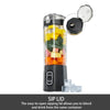 Portable electric fruit mixer with sip lid open showing flip-top drinking spout, filled with chopped vegetables and ice cubes, Auto and Pulse buttons visible, white background