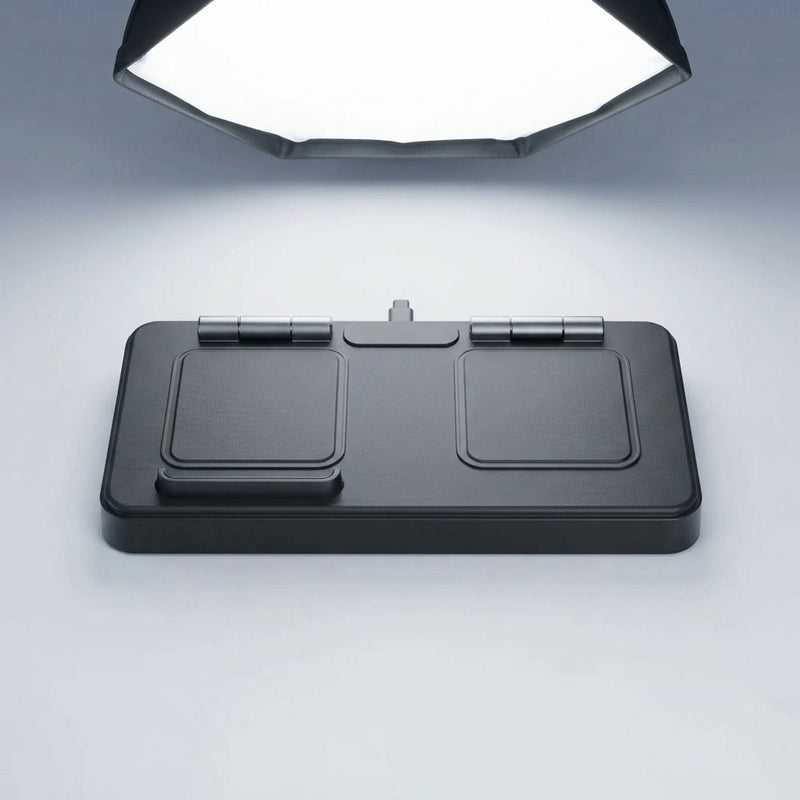 Foldable magnetic wireless charging station in flat/folded position showing two square charging pads and center hinge with USB-C port, on grey background under studio lighting